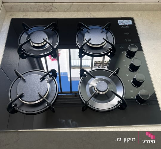כיריים גז שחורות עם ארבעה מבערים וכפתורי שליטה